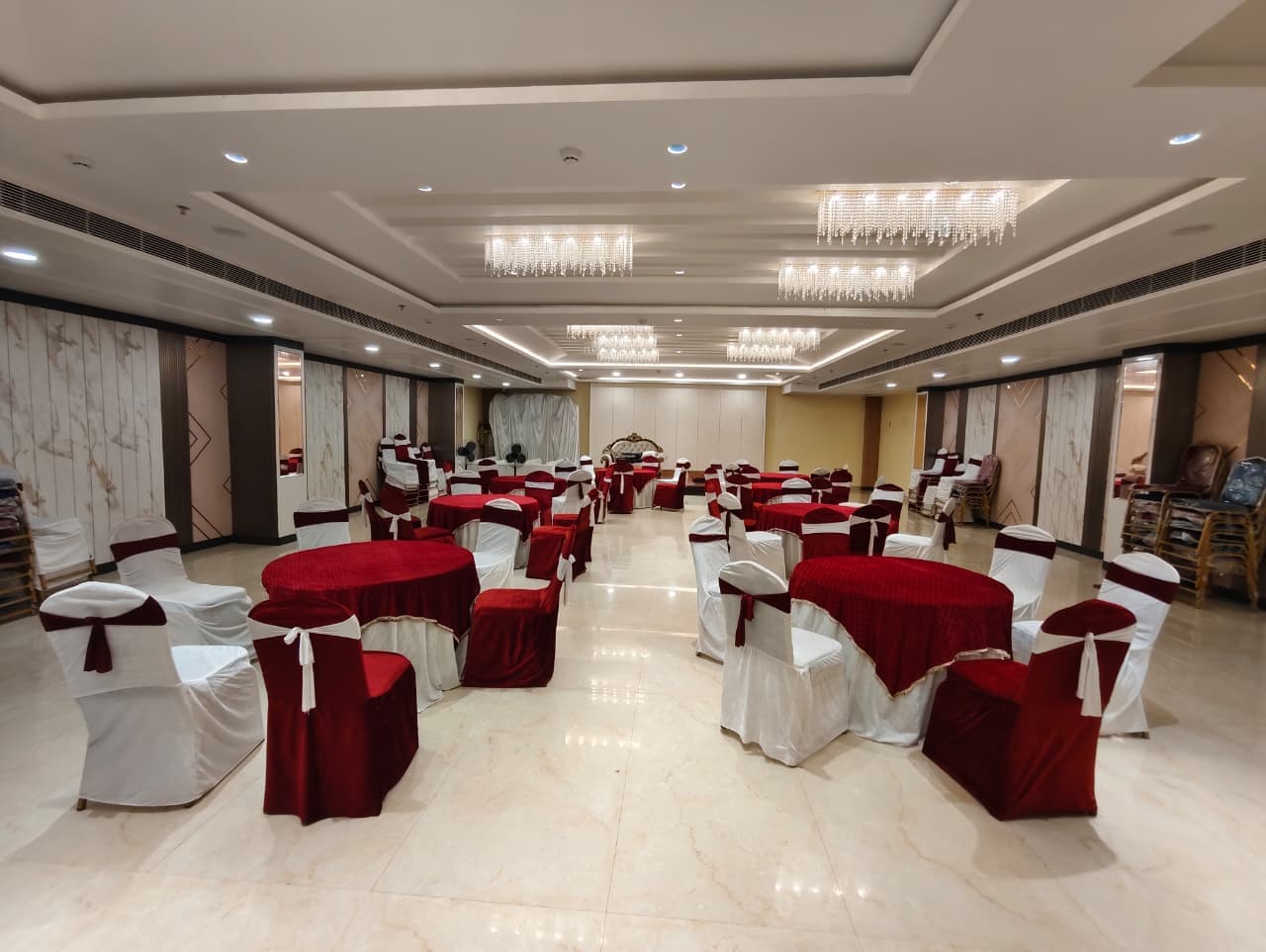 Elegant banquet hall featuring red and white table settings and sparkling crystal chandeliers.
