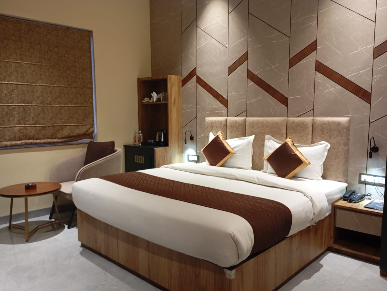Modern hotel room with a large bed, brown accents, and a geometric patterned wall.