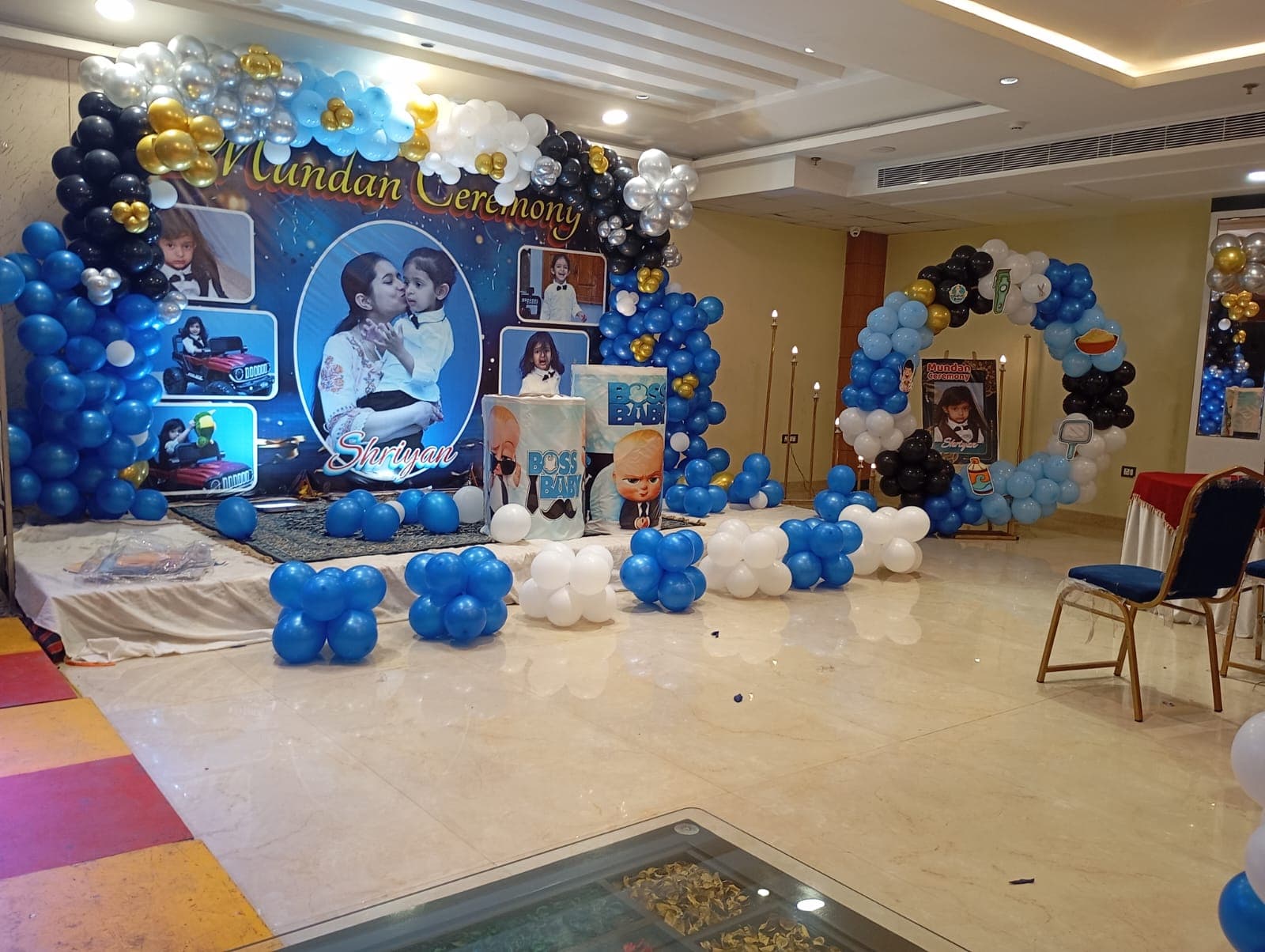 Mundan ceremony stage with blue and white balloon arches and Boss Baby themed backdrop.